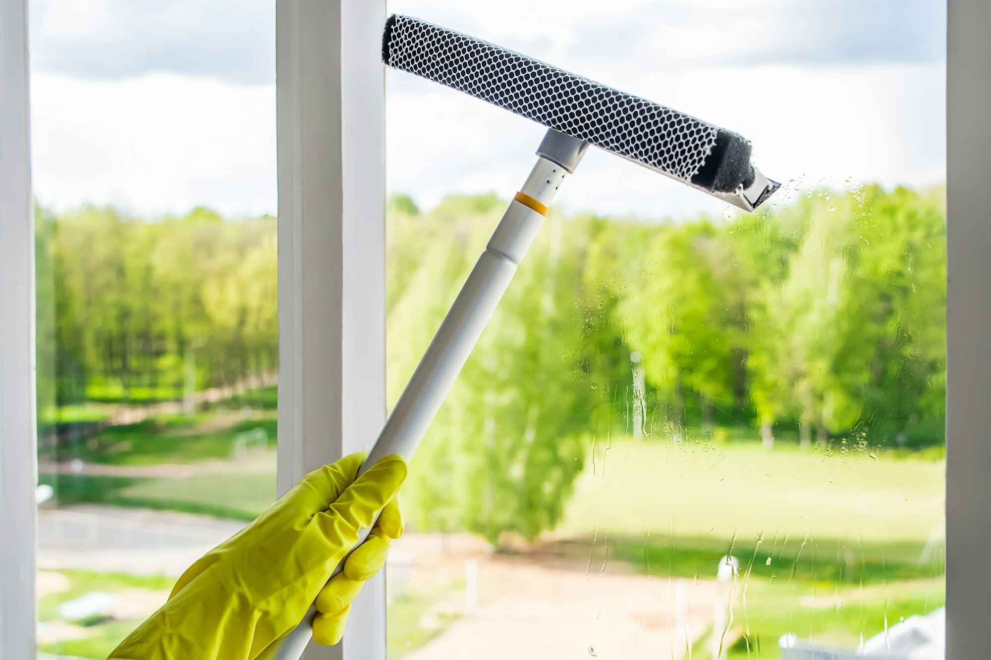 Window washing and home cleaning. Woman sprays a detergent on a glass. Housework concept.